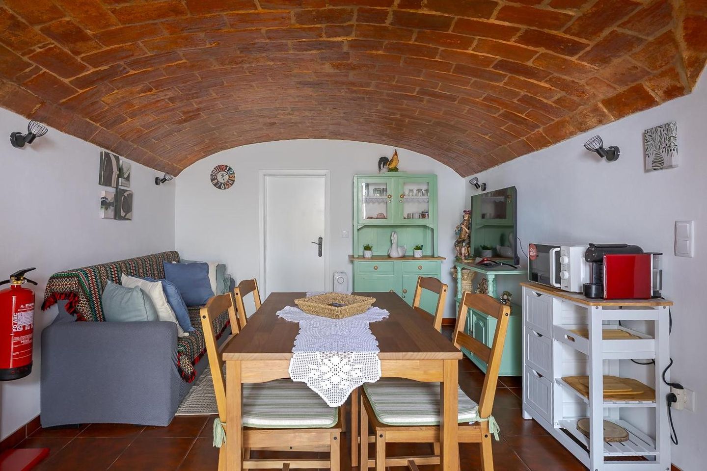 Sala com cozinha sob o teto em abóbada de tijolo, com mesa de refeições e sofá