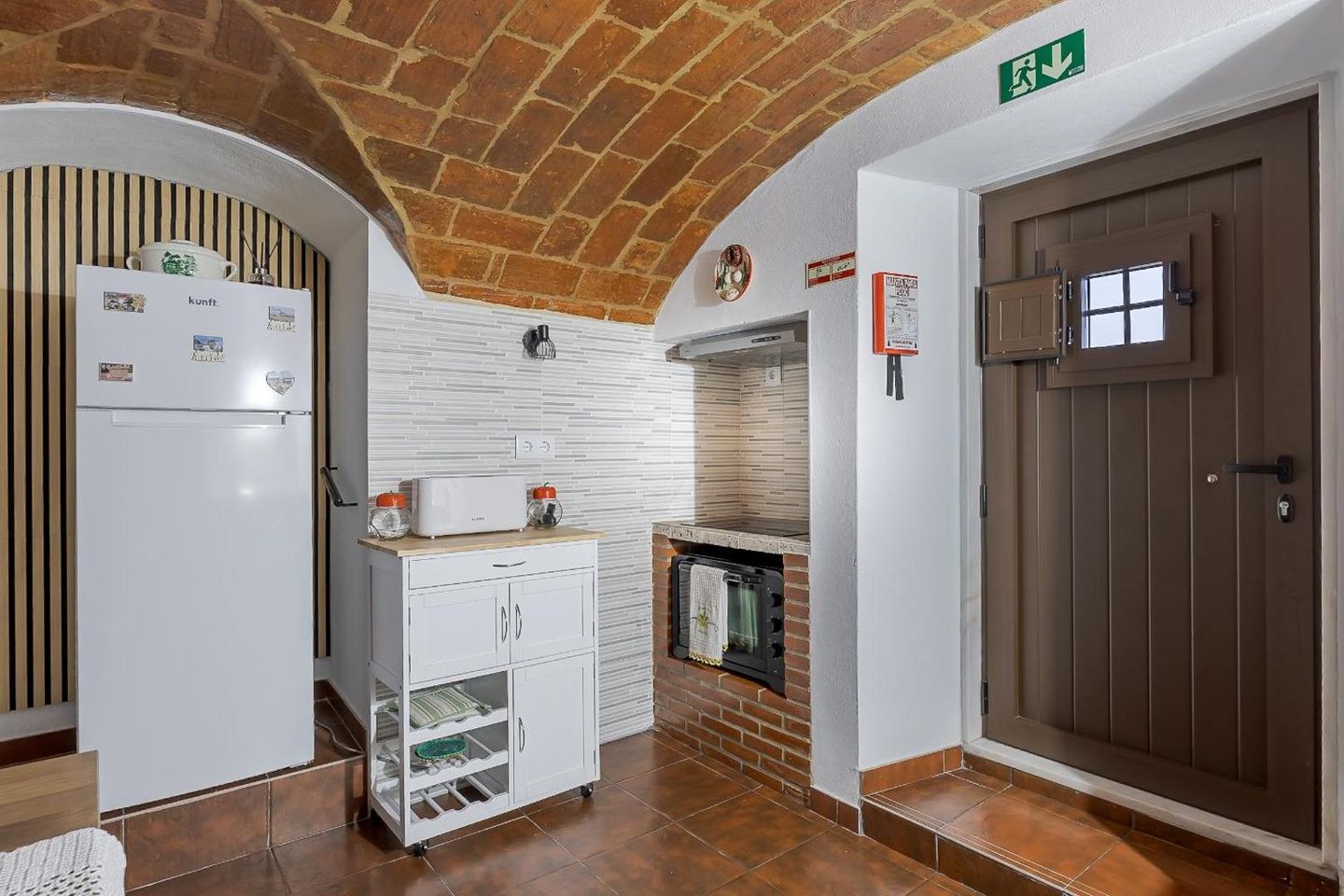 Cozinha equipada com frigorífico, micro-ondas e porta de madeira antiga