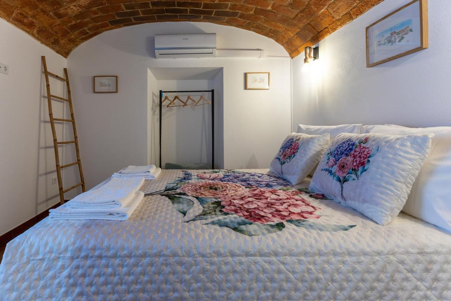 Quarto de casal com teto em abóbada de tijolo e colcha de flores