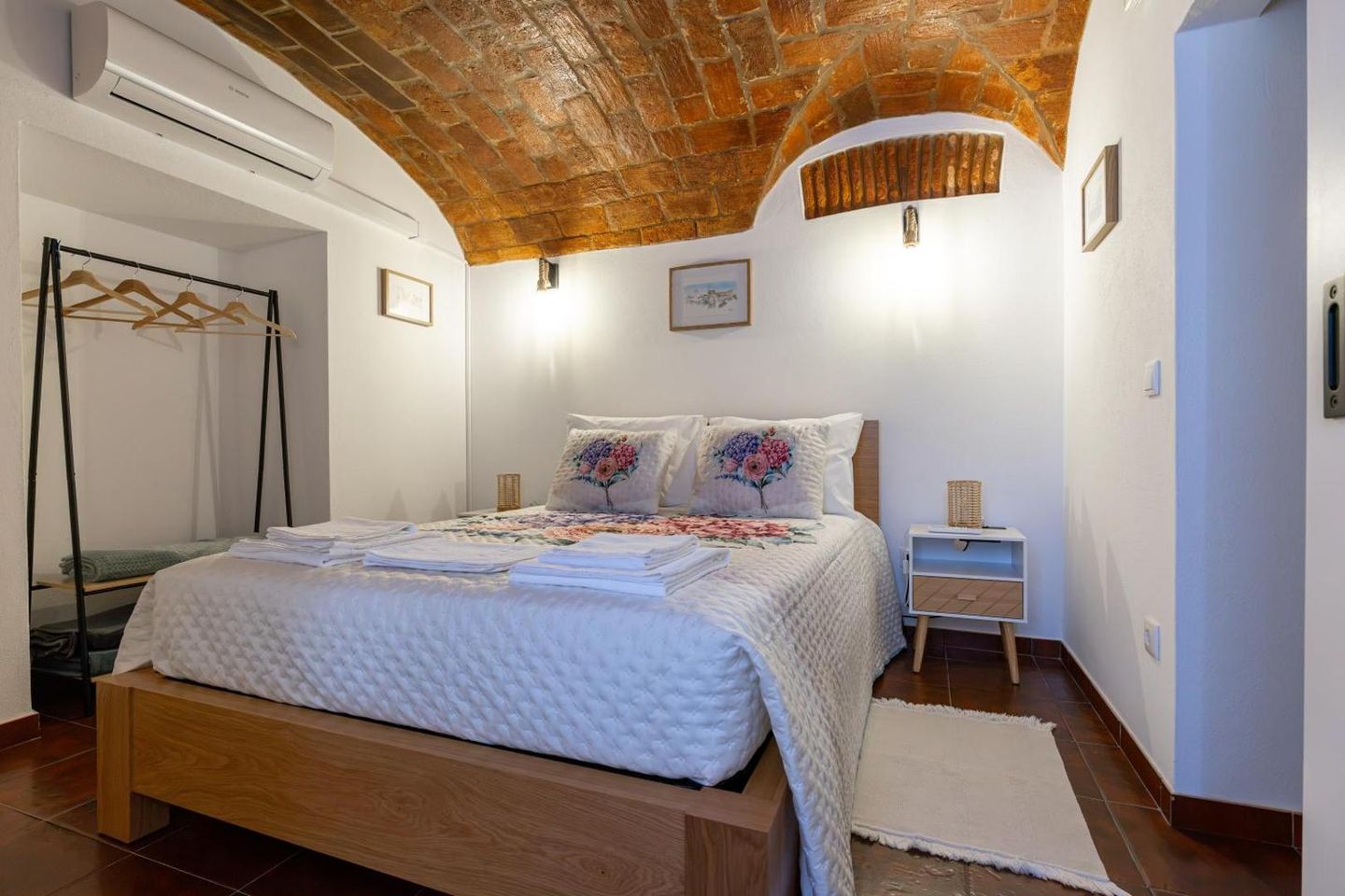 Quarto de casal com ar condicionado, cabide de madeira e teto em abóbada