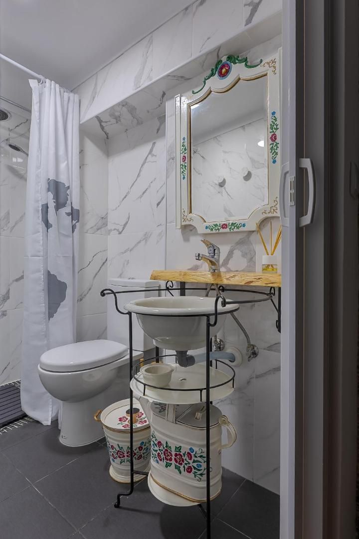 Casa de banho em mármore branco com lavatório e espelho de moldura trabalhada